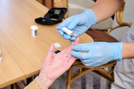 Pflegerin untersucht den Blutzuckerspiegel einer Klientin: Erfahrene Pflegekräfte