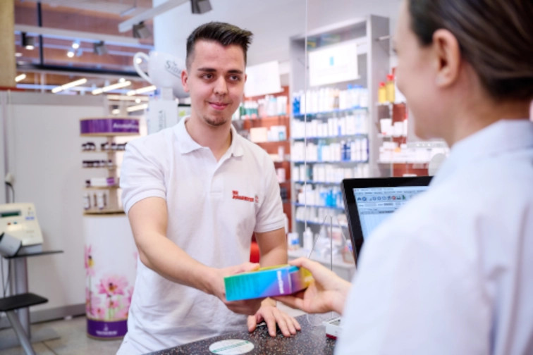 Pfleger holt Medikamente in einer Apotheke ab: Mobile Hauskrankenpflege